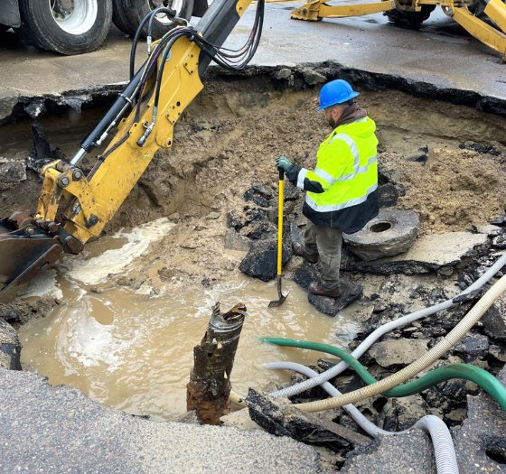 worker and shovel inside of sinkhole