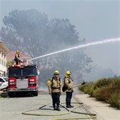 fire engine pumps water onto brush fire