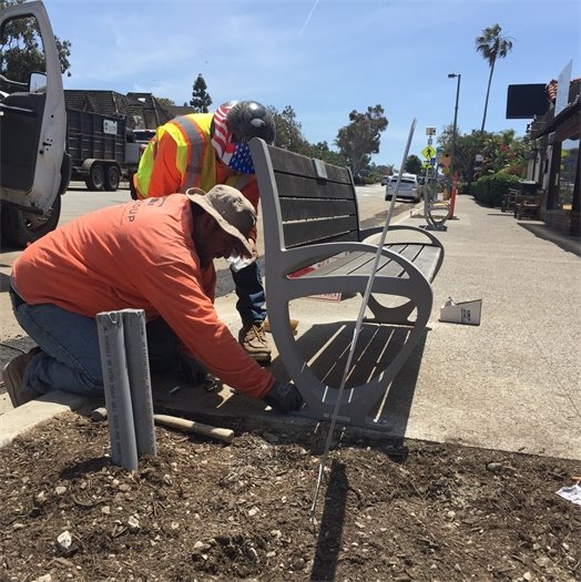 Workers bolt bench onto sidewak