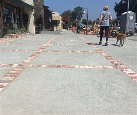 woman walks dog on new sidewalk